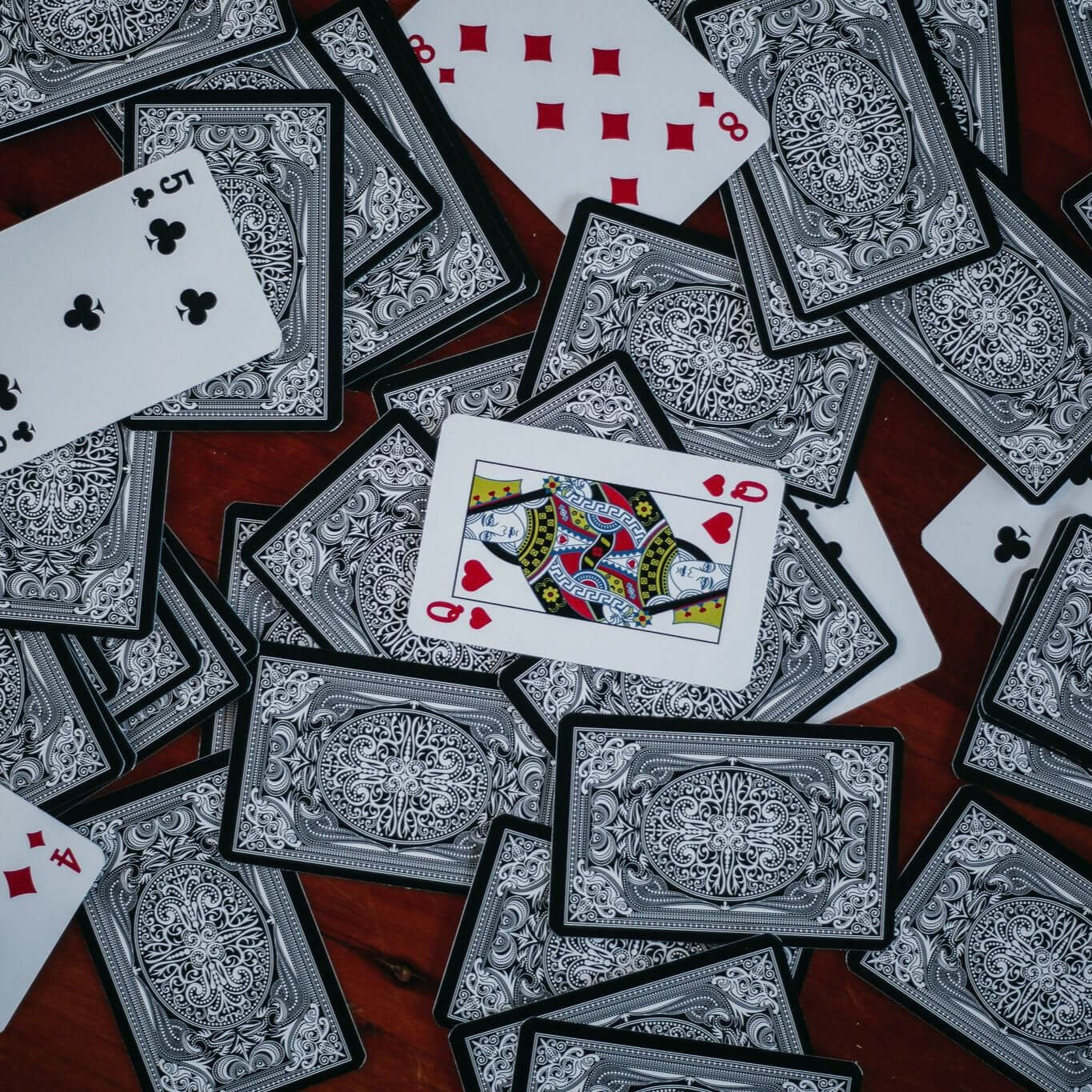 Custom poker-sized playing cards with intricate designs scattered on a table.