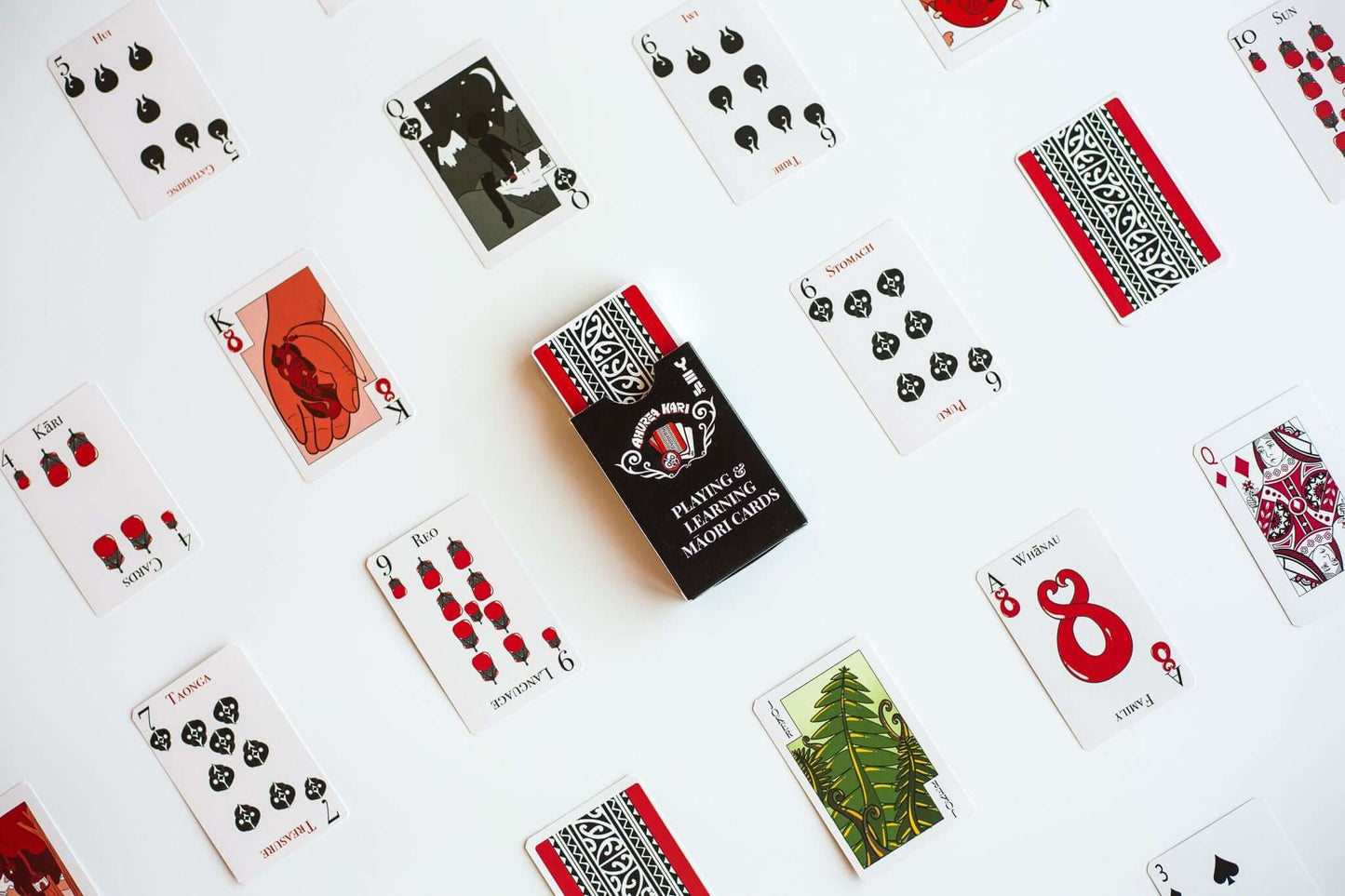 Custom poker-sized playing cards with unique designs and printed box, laid out on a white surface.