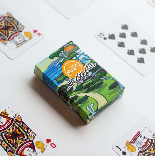 Custom poker-sized playing cards with colorful box and card designs displayed on table.