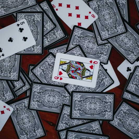 Custom poker-sized playing cards with intricate designs scattered on a table.